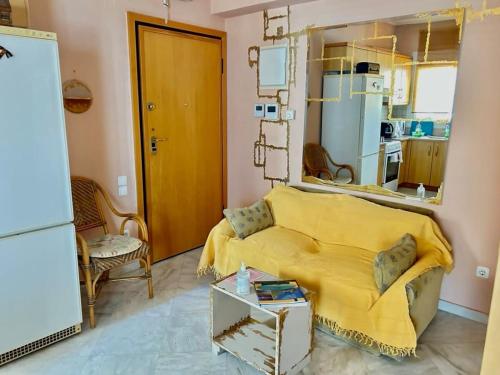 a living room with a yellow bed and a refrigerator at Chios Cozy studio Island Getaway in Chios