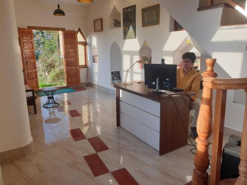 a man sitting in front of a computer in a room at Naldehra House in Shimla