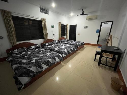 um grupo de camas num quarto com uma secretária em Errol's Homestay and Hostel em Siem Reap