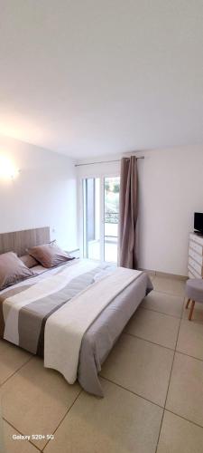 un grand lit dans une chambre avec une fenêtre dans l'établissement Appartement T2 centre ville Île Rousse, à LʼÎle-Rousse