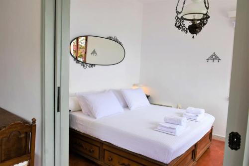a bedroom with a bed with white sheets and a mirror at Anthi's Villa in Achladies