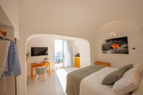 1 dormitorio con cama, escritorio y ventana en Villa Francesco Luxury Suites, en Positano