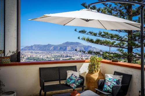 um pátio com um guarda-sol, cadeiras e uma mesa em Villa Rosa Bianca em Palermo