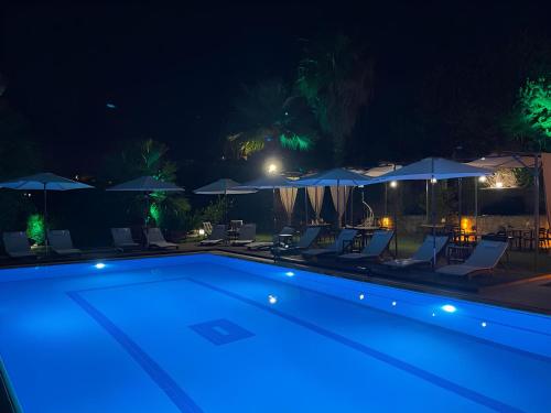 a swimming pool at night with chairs and umbrellas at MAVİ ROTA BUTİK OTEL in Datca