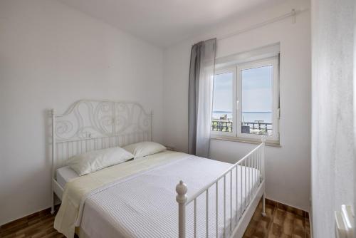 une chambre blanche avec un lit et une fenêtre dans l'établissement Mediterano Apartments, à Podstrana
