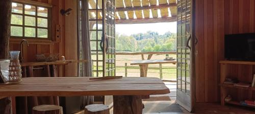 Habitación con mesa de madera y ventana grande. en Cabanes des Landes- cabane sur pilotis, en Saint-Éloy-les-Tuileries