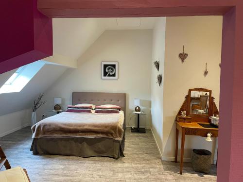 ein Schlafzimmer mit einem großen Bett und einem Schreibtisch in der Unterkunft Les Myosotis Chambres d'hôtes - Sarreguemines in Zetting