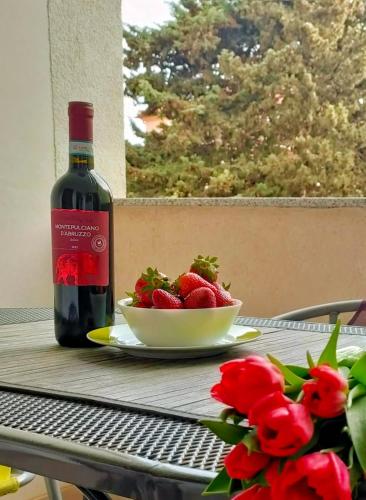 a bottle of wine and a bowl of strawberries on a table at Rafael Apartments in Medulin
