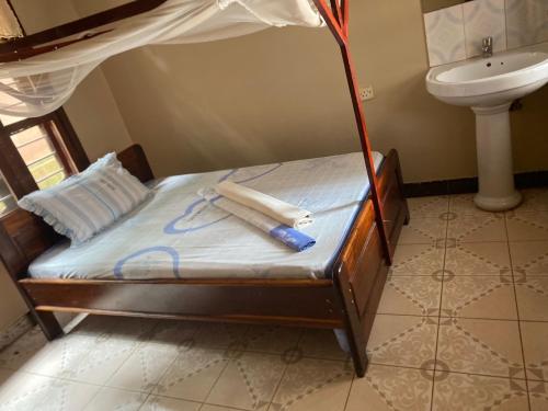 Bett in einem Zimmer mit Waschbecken und Bett mit Baldachin in der Unterkunft Nzimano Hostel in Kigoma