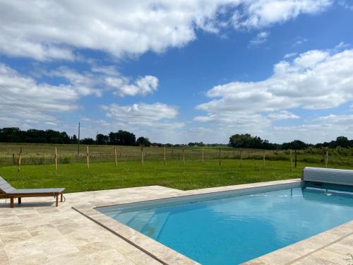 a swimming pool with a bench next to a field at Domaine de Rébert in Monguillem