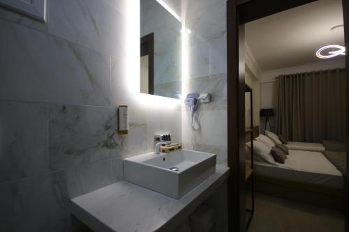 a bathroom with a sink and a mirror and a bed at ARXONTIKO in Himare
