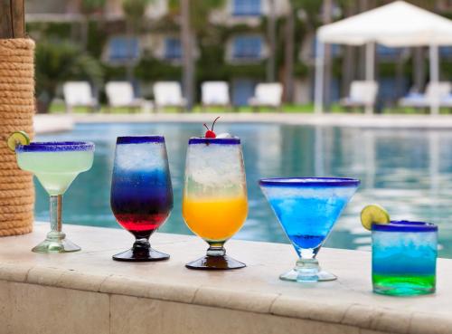 a group of different colored glasses sitting on a table near a pool at Loreto Bay Golf & Sea at Baja in Loreto