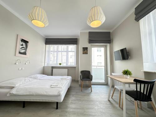 a bedroom with a bed and a desk and chairs at Baltic Plaza Gdynia - MAXIMAL in Gdynia
