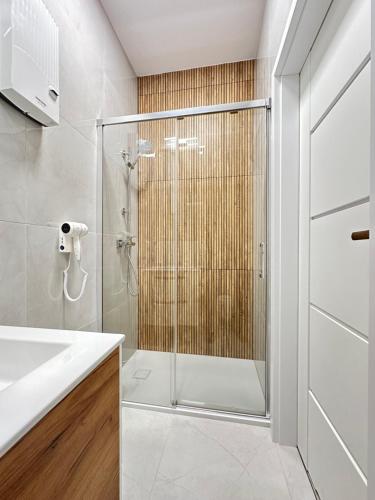 uma casa de banho com um chuveiro e uma porta de vidro em Baltic Plaza Gdynia - MAXIMAL em Gdynia