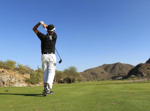 a man swinging a golf club on a golf course at Loreto Bay Golf & Sea at Baja in Loreto