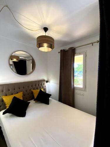 - une chambre dotée d'un lit blanc avec des oreillers jaunes et un miroir dans l'établissement Appartement le Swing de Bacchus, à Deauville