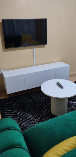 uma sala de estar com um sofá, uma mesa e uma televisão em COMFORT CORNER em Juja