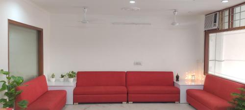 une salle d'attente avec deux canapés rouges et une fenêtre dans l'établissement Hotel SPR Near Delhi Airport -Unit of Soft Petal Residency, à New Delhi