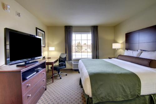 a hotel room with a bed and a flat screen tv at Cobblestone Inn & Suites - Hartington in Hartington