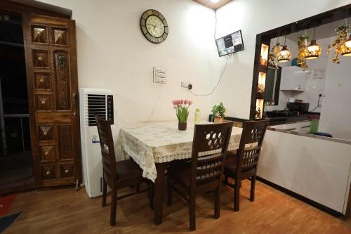 a dining room table with chairs and a clock on the wall at Sundarbagh farmhouse in Khamshet