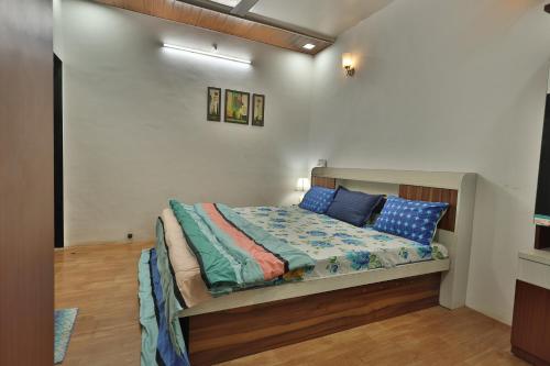 a bedroom with a bed with blue pillows on it at Sundarbagh farmhouse in Khamshet