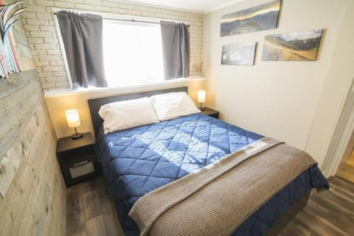 a bedroom with a bed with a blue comforter and a window at Cozy Main St 1BR Next to Ski Access and FREE Shuttle in Breckenridge