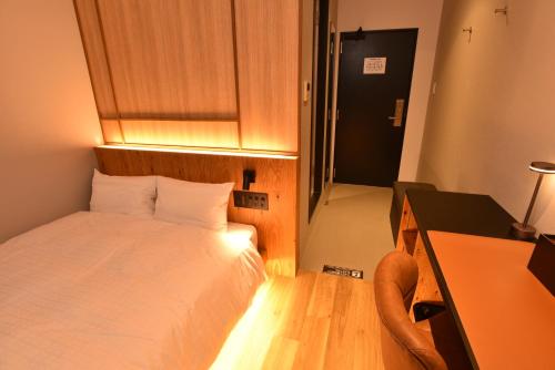 ein kleines Schlafzimmer mit einem Bett, einem Schreibtisch und einem Schreibtisch in der Unterkunft ArC LIFESTYLE SPACE & HOTEL in Mito