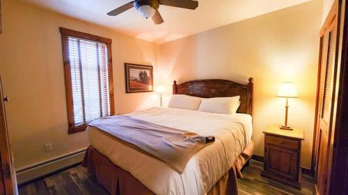 a bedroom with a bed with a ceiling fan and a window at Main St Station Condo with Hot Tub and Parking in Breckenridge