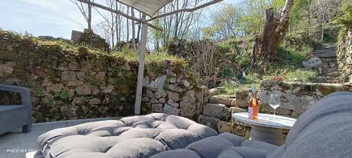 un patio avec un canapé et une table et un mur en pierre dans l'établissement Le Temps Suspendu, à Saint-Pierreville