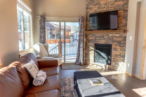 a living room with a leather couch and a fireplace at 2BR Riverside Chalet Near Trails in Breckenridge