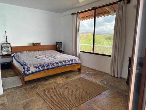 a bedroom with a bed and a large window at VILLA FLOREANA in Puerto Velasco Ibarra