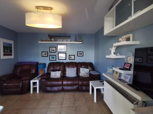 a living room with a leather couch and a tv at Coral Cove Bundoran in Bundoran
