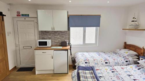 a small bedroom with a bed and a kitchen with a microwave at Four Winds Holiday Let in Nairn