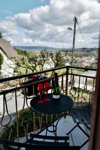 two wine glasses and a bottle on a table on a balcony at Maison au cœur des vignes in Épernay