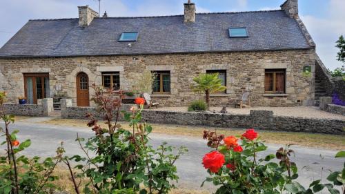 an old stone house with red flowers in front of it at Appartement Le camélia blanc in Corseul