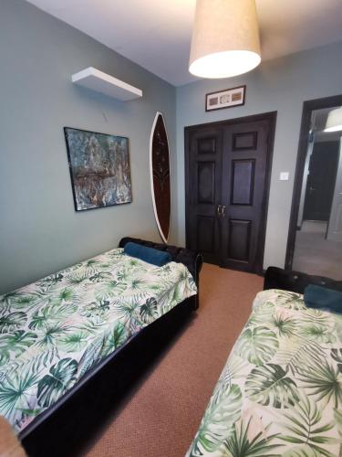 a bedroom with two beds and a door at Palm Cove Bundoran Luxurious Sea View Balcony Free Wifi Netflix Sleeps 5 in Bundoran
