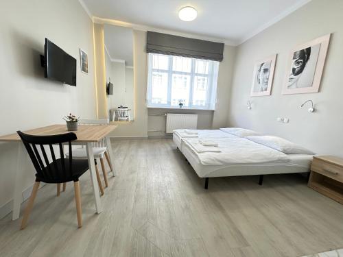 a bedroom with a bed and a desk and a table at Baltic Plaza Gdynia - MAXIMAL in Gdynia