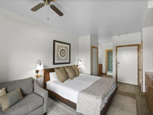 a bedroom with a bed and a couch and a ceiling fan at Ski in Ski Out Studio with Balcony and Hot Tub Access in Park City