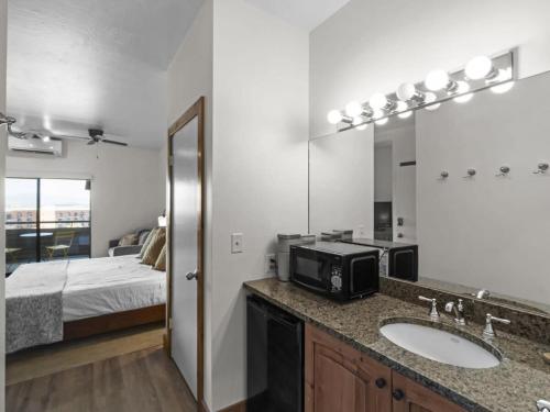 uma casa de banho com um lavatório e um quarto com uma cama em Cozy 1BR Resort Living with Ski Lift Seconds Away em Park City