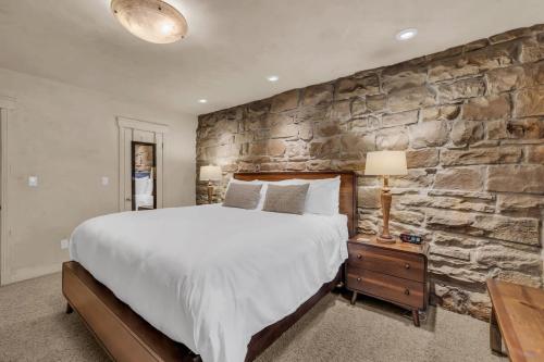 a bedroom with a large bed and a stone wall at Rustic 2BR Steps from Main St in Park City