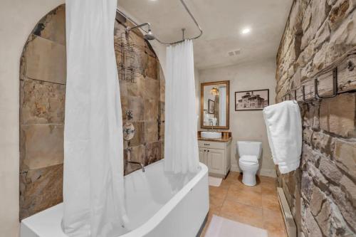 a bathroom with a tub and a stone wall at Rustic 2BR Steps from Main St in Park City