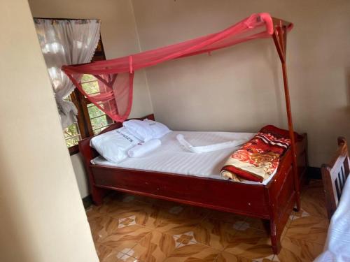 a small bed with a canopy in a room at Nzimano Hostel in Kigoma