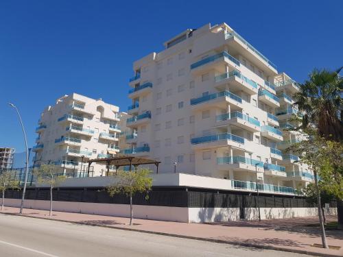 un edificio de apartamentos alto y blanco en una calle de la ciudad en Apartamento Blau Mar en Piles