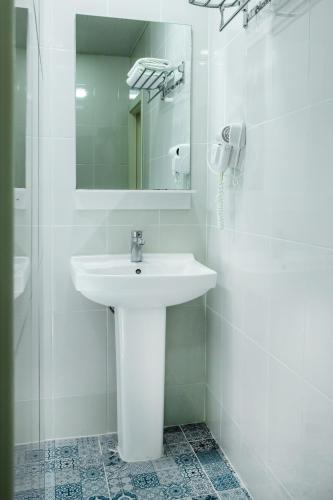 a white bathroom with a sink and a mirror at Moss Art Boutique Hotel in Baku