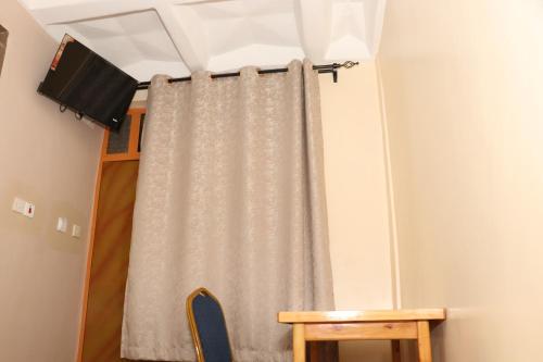 einen Vorhang in einem Zimmer mit einem Tisch und einem Tisch in der Unterkunft Motel Clavina in Gilgil