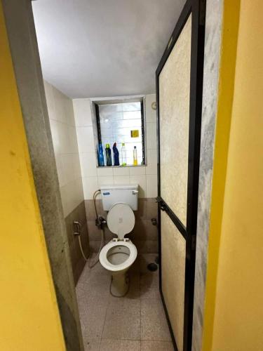 a small bathroom with a toilet and a window at F2 apartments in Mumbai