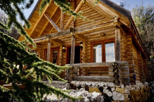 a log cabin with a christmas tree in front of it at Wood Hills Hotel & Resort in Mayrūbā