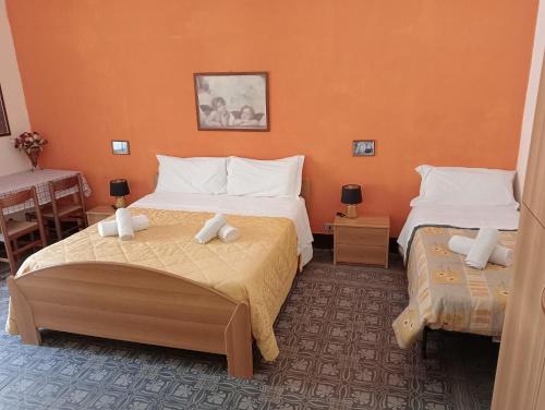 twee bedden in een kamer met oranje muren bij La locanda in Cefalù