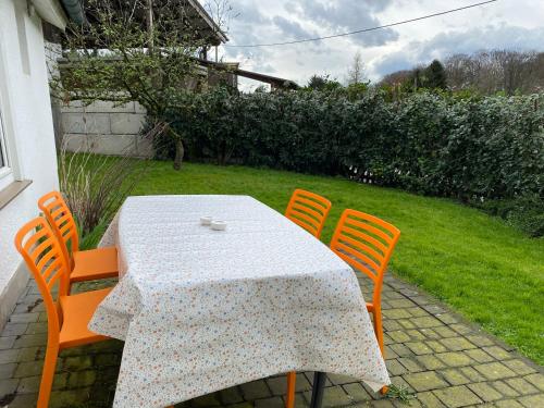 mesa con 4 sillas naranjas y mesa con mantel blanco en Ferienhaus Wietsche, en Burscheid
