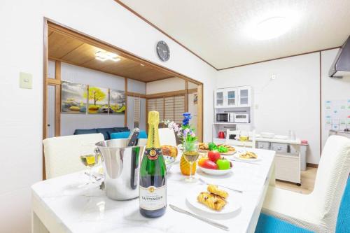 a white table with a bottle of wine and food on it at 源泉かけ流し温泉付き貸し切り別荘白浜観光に最適の立地14名宿泊可能 in Shirahama